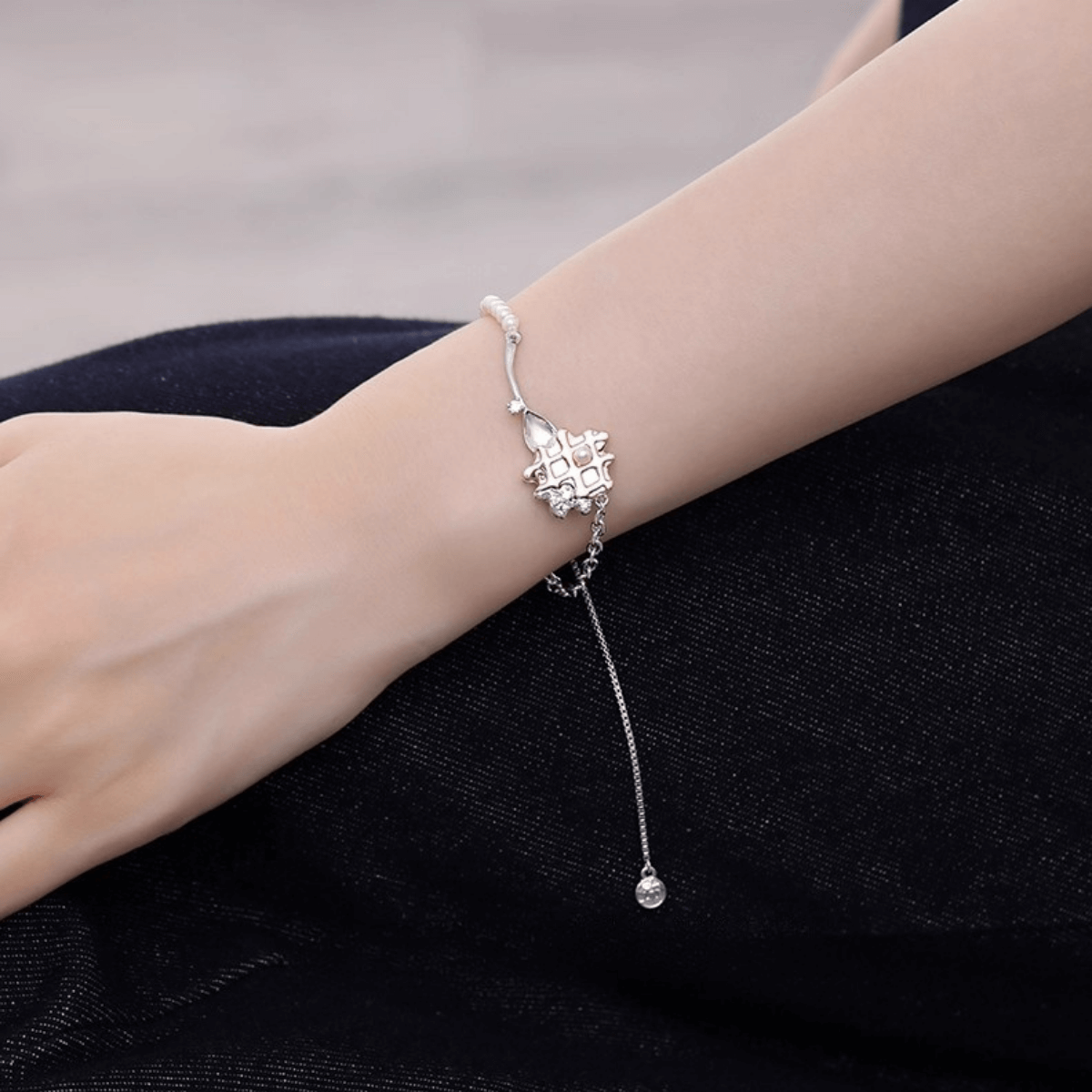 Close-up of a woman's wrist wearing the elegant Enola & SHE Waffle Pearl Bracelet with an adjustable chain.